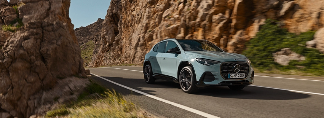 Nuova Mercedes GLA 2026 azzurra in movimento su strada di montagna, vista tre quarti anteriore