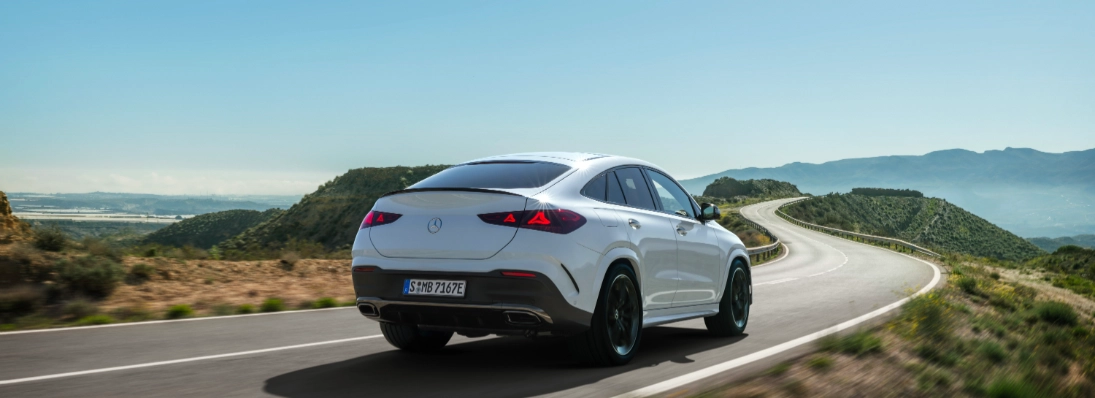Mercedes GLE Coupé bianca in movimento su strada di montagna, vista posteriore