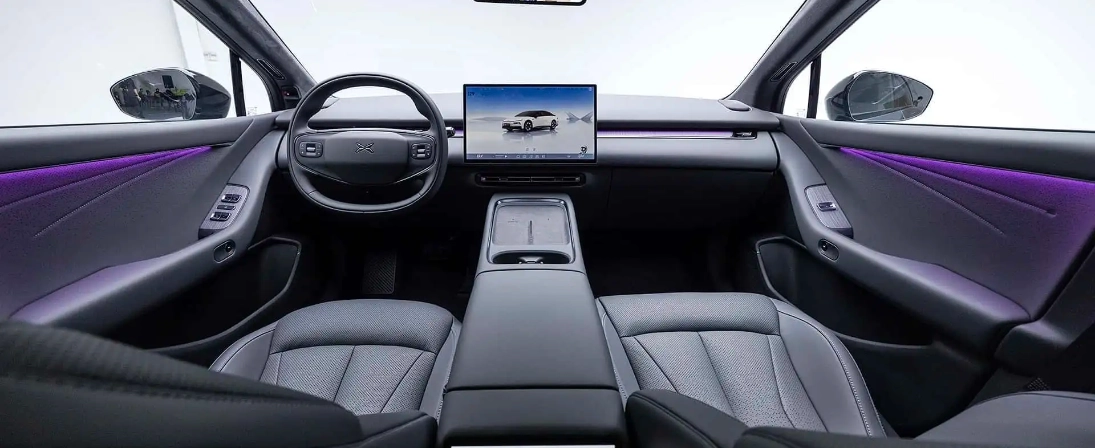 Interni XPENG P7+ con display centrale, volante e illuminazione ambientale viola
